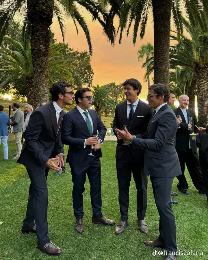 Hombres con trajes oscuros y corbata en un jardín
